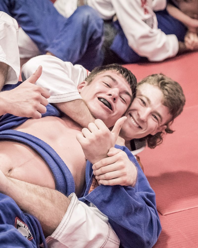 Two members in blue gis laughing during Brazilian Jiu Jitsu training at Chau Kaizen in Prospect, Adelaide